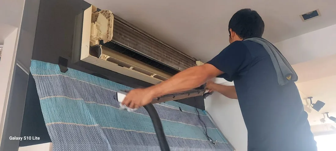 Kim's Aircon technician steam-cleaning a wall-mounted aircon indoor unit in a Singapore home